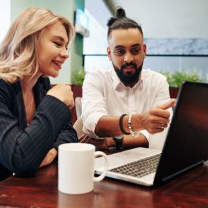 Two people at a table reviewing material on a laptop